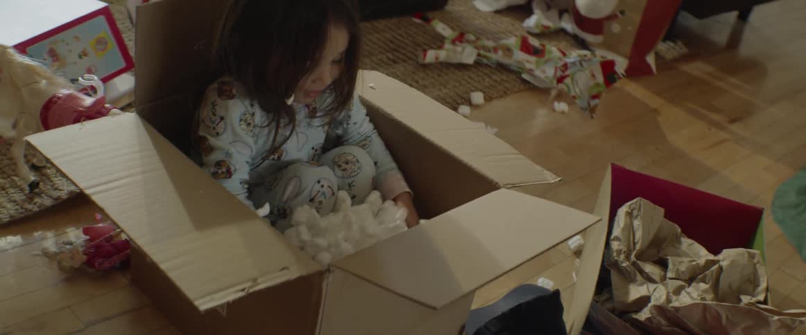 Little girl plays in a box of packing peanuts
