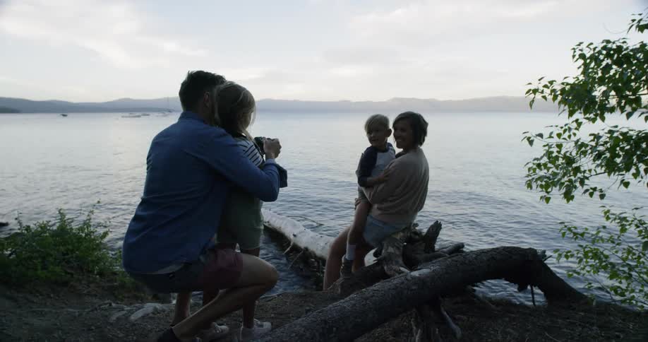 Father and daughter photograph mother and son next to lake