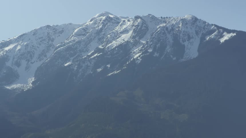 Mountains partially covered in snow on sunny day