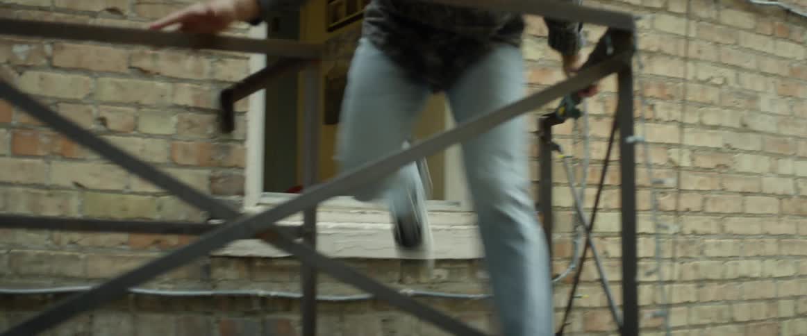 A young man flees through an apartment window down a fire escape