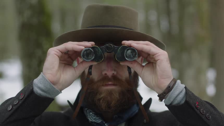 Man standing outside is looking through binoculars