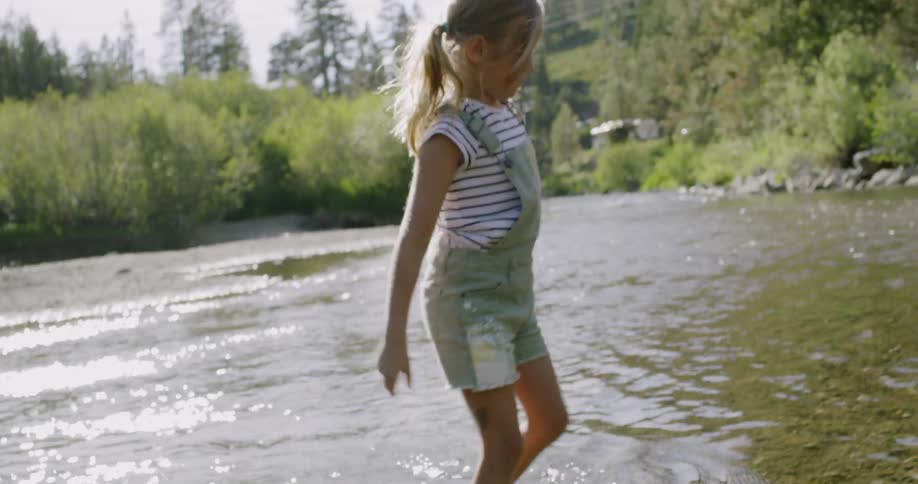 A girl wades in the river on a sunny day