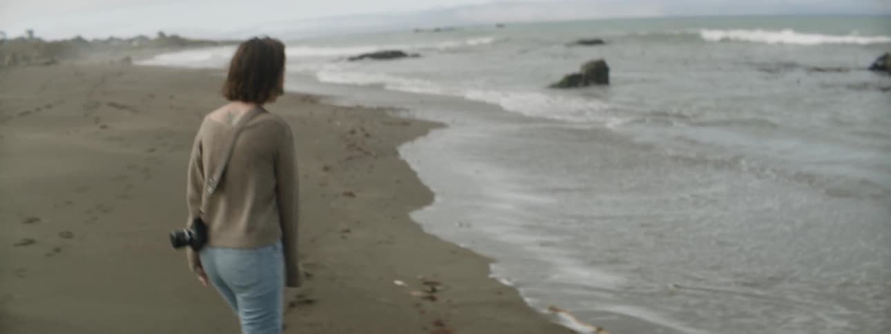 A woman is walking along the beach