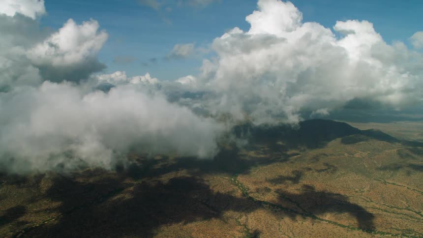 Clouds are casting shadows on a mountain landscape during the day
