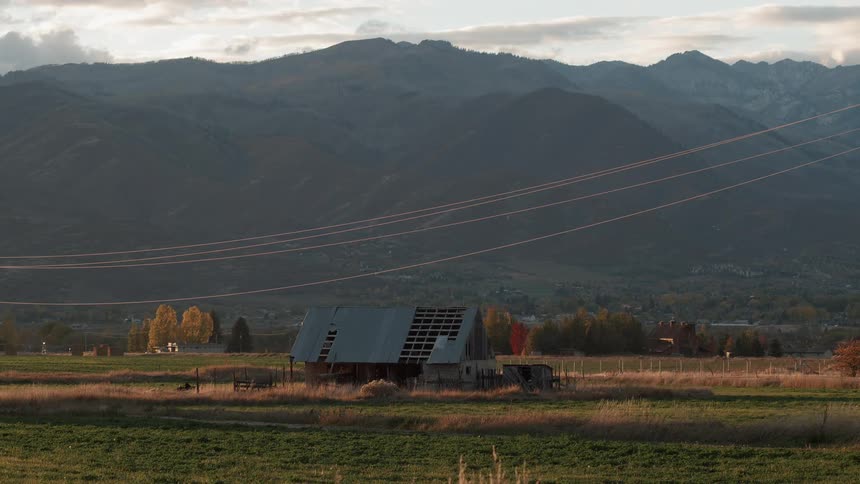Farm building with some of its roof missing on a cloudy fall day