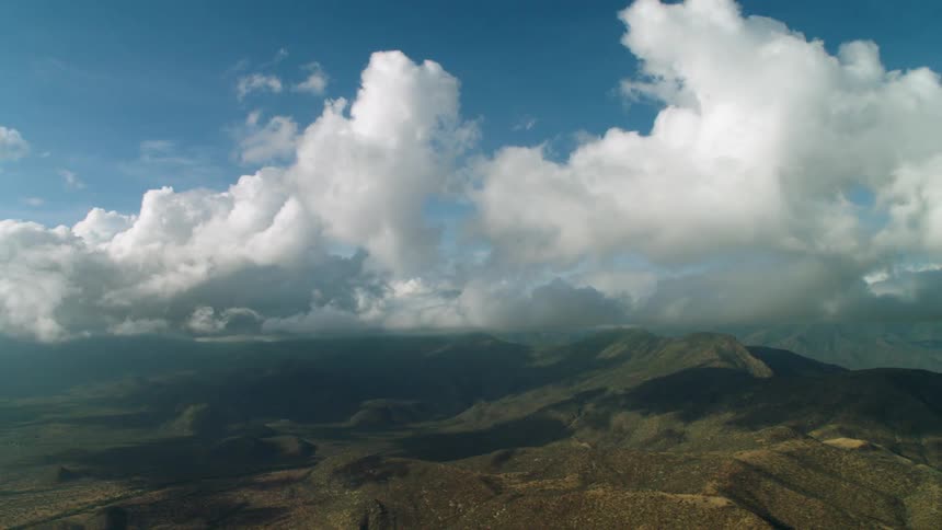 Clouds float over brown hilly land
