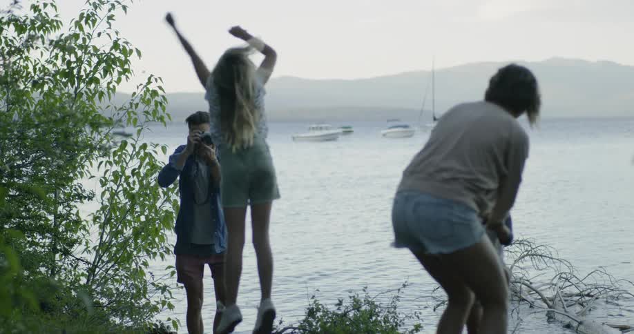 Child jumps and man films her near the water
