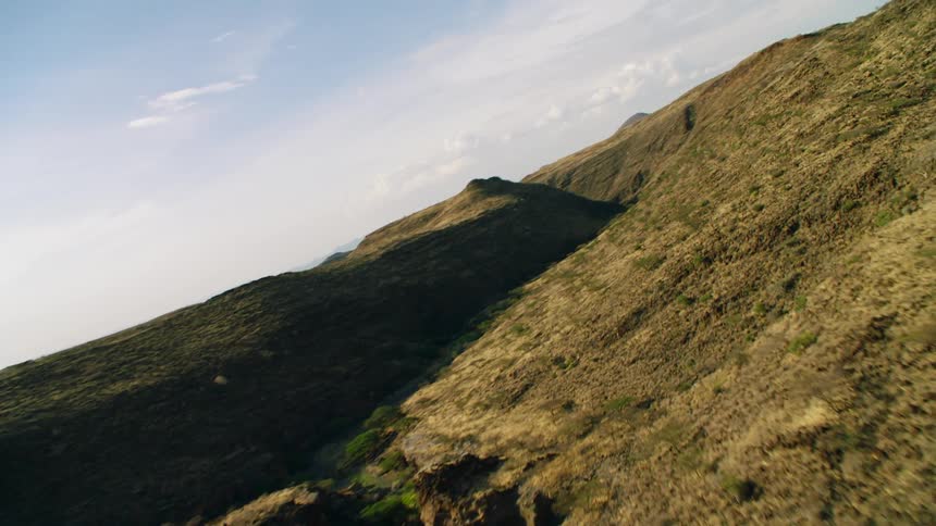 Hilly grassy land with clouds overhead