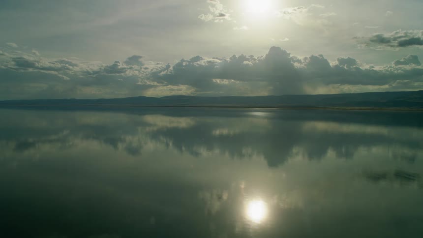The sun is reflecting on a lake on a cloudy day