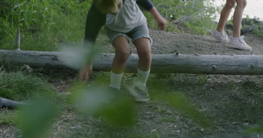 Child jumps over a fallen log