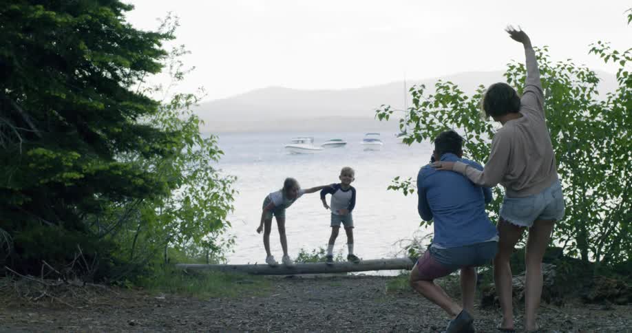 A mother is waving at her children as they pose in a natural setting for their father