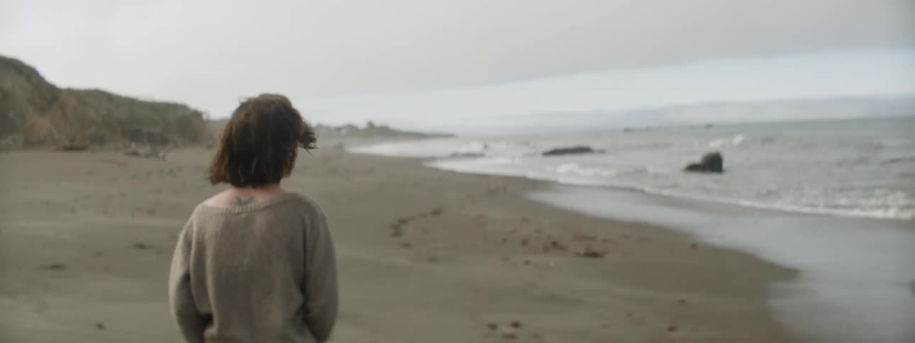 Woman walks on a beach on a cloudy day
