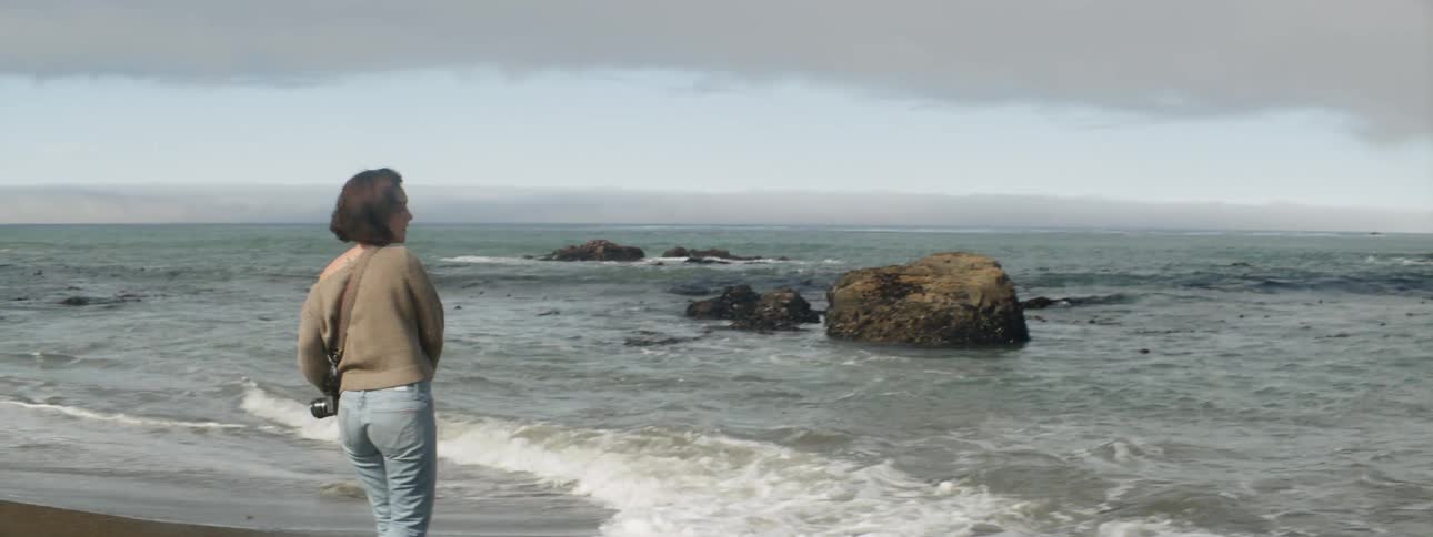 Woman throws a rock into the ocean