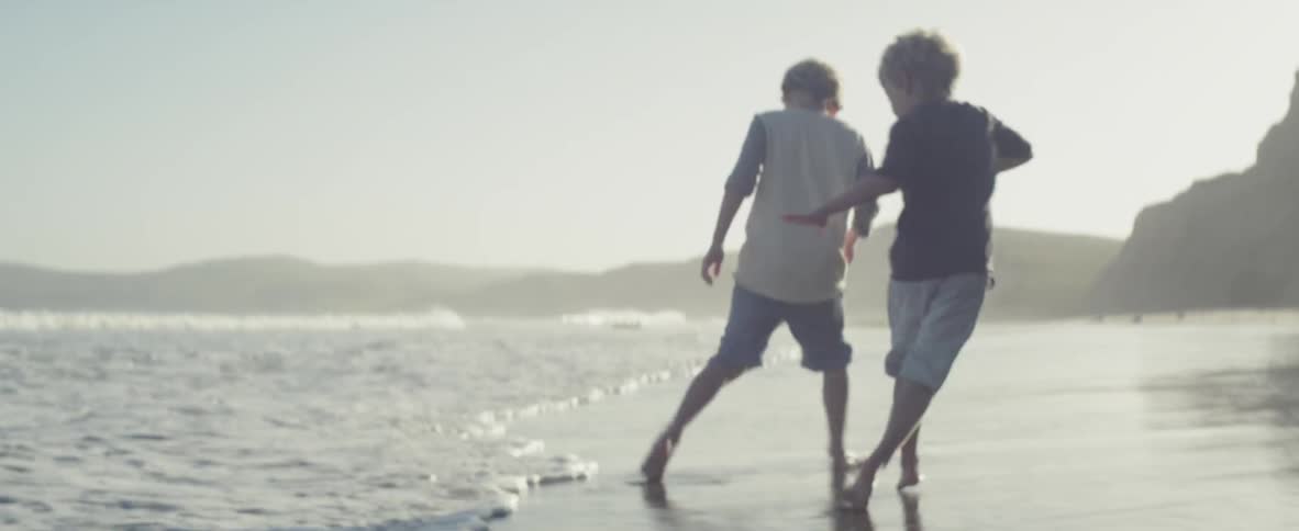 Father and boys playing on beach and avoiding incoming waves