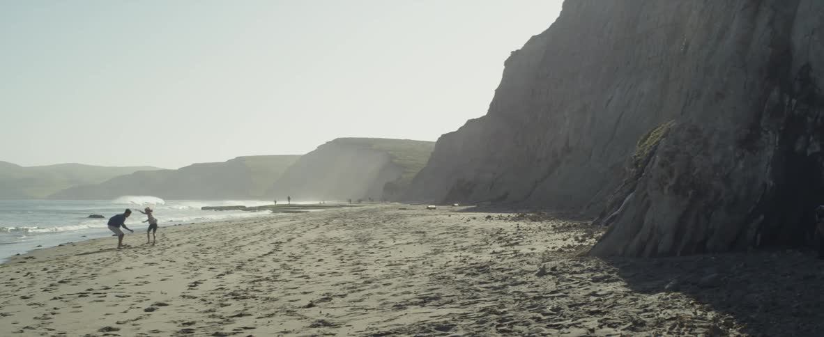 A dad plays with his daughter on the beach