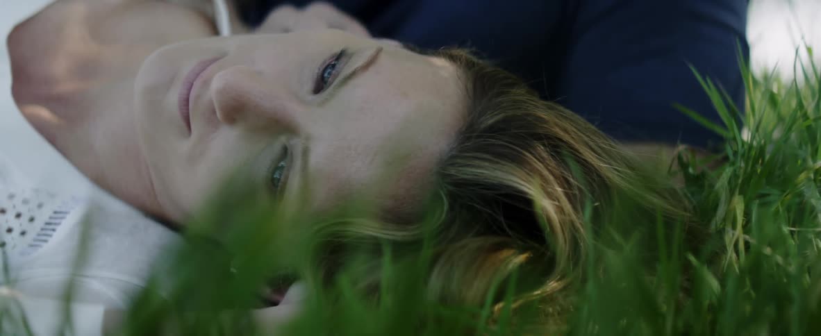 Woman sleeps on the grass as a hand touches her hair