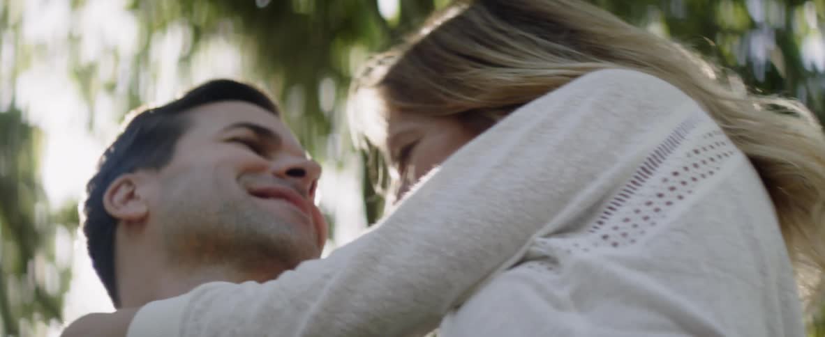 A couple hug under a tree in the sunshine