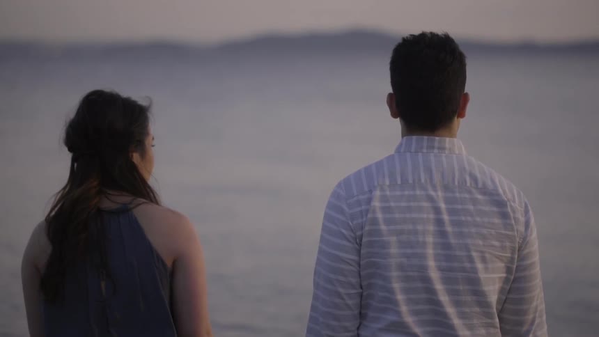 A man and a woman stand outdoors and look off into the distance