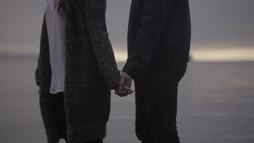 Man and woman holding hands by the water