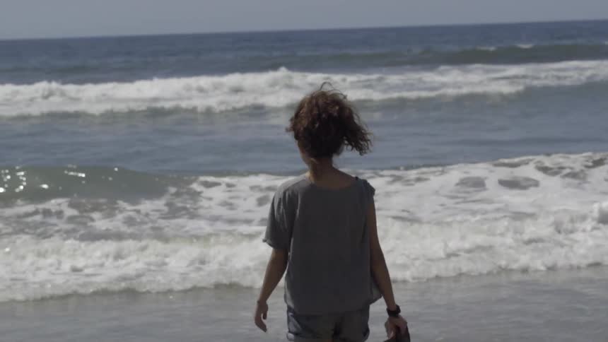 A girls walks towards ocean waves