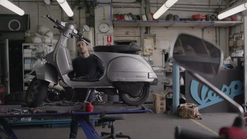 Man fixes on a small motorbike in a garage