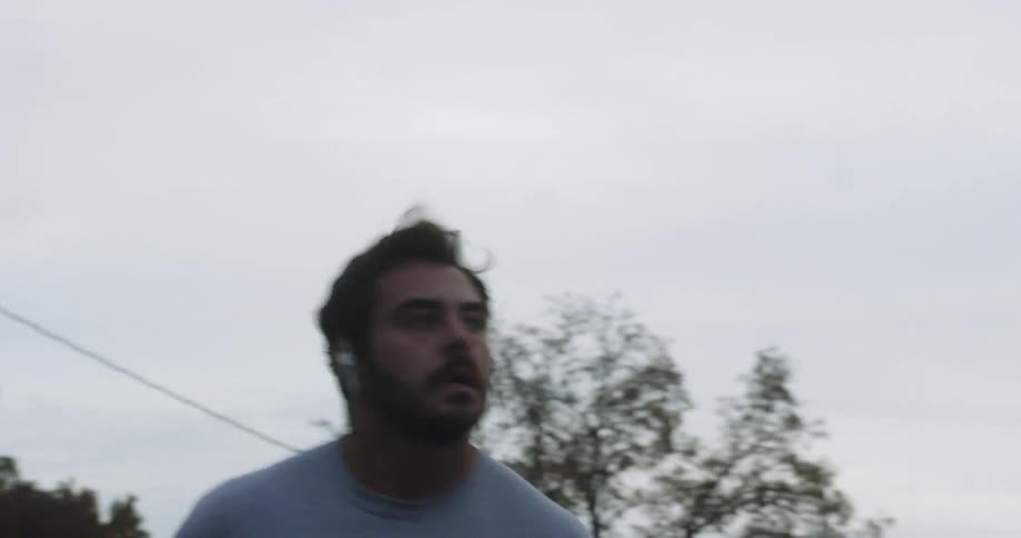 Man jogs in a neighborhood on a cloudy day