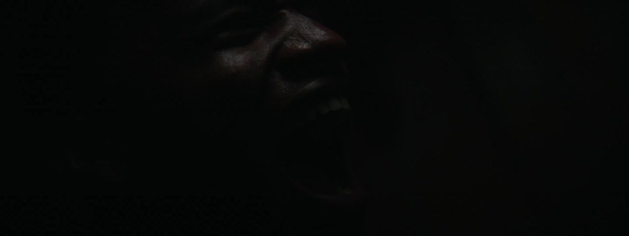 Man screaming in a dark room