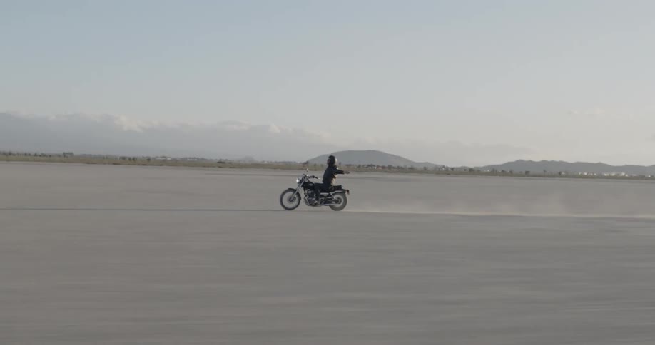 A person races their motorcycle in the desert