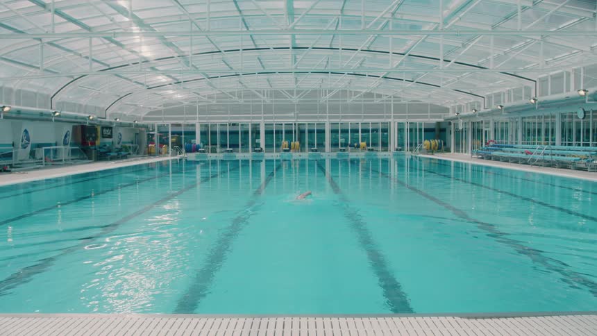 Person is front crawl swimming in large indoor lap pool