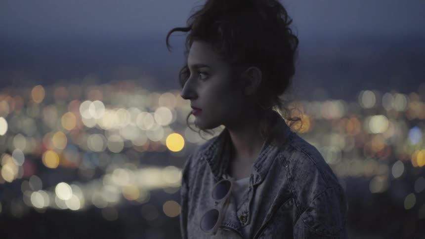 A woman standing on a balcony high above the city