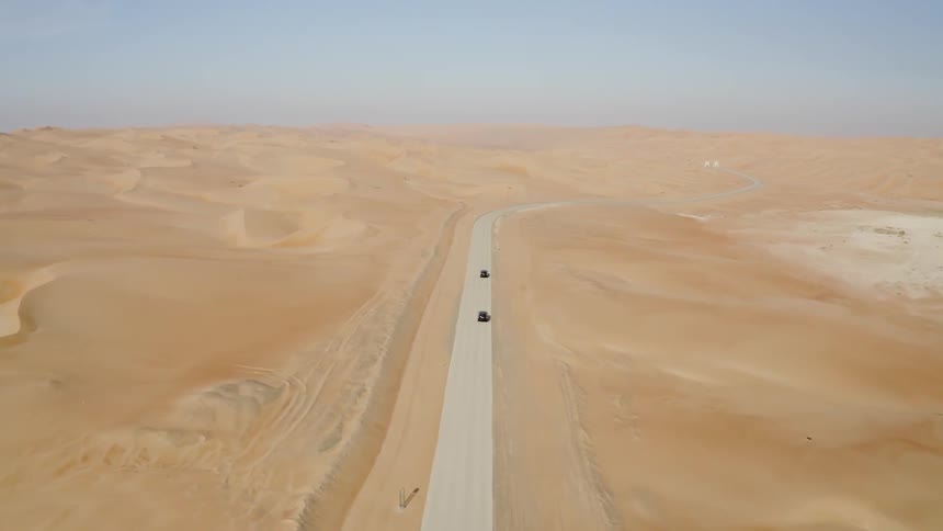 Two cars travel on an empty desert road