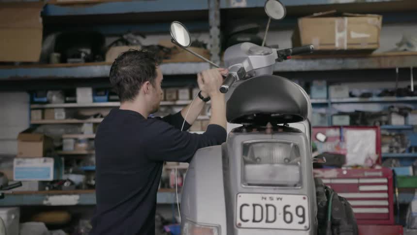 Two men fix a small gray motorbike