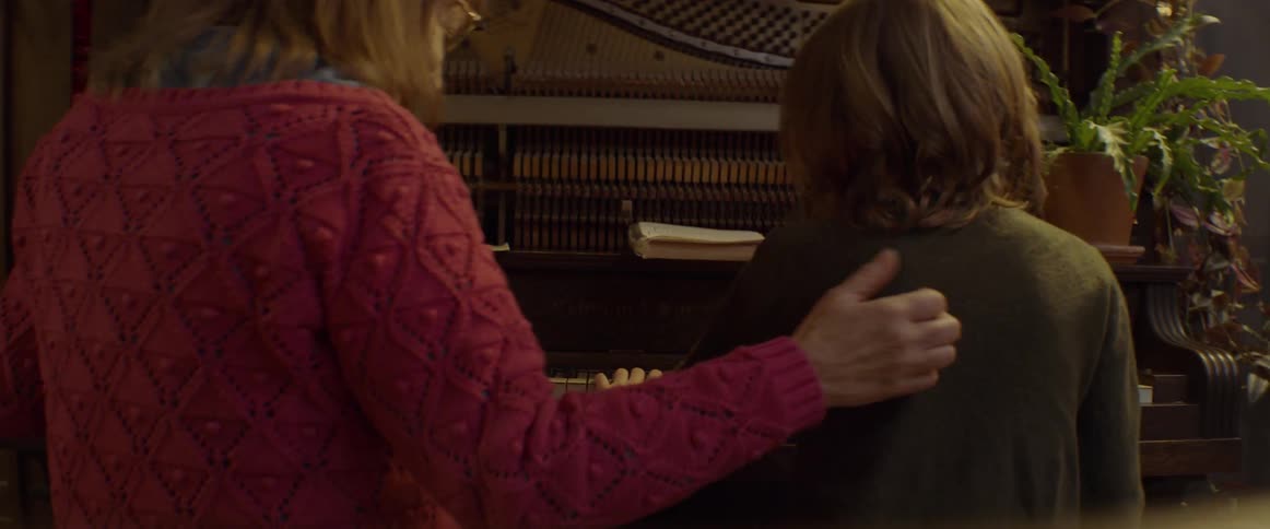 Child practices the piano and a woman sits down to play too