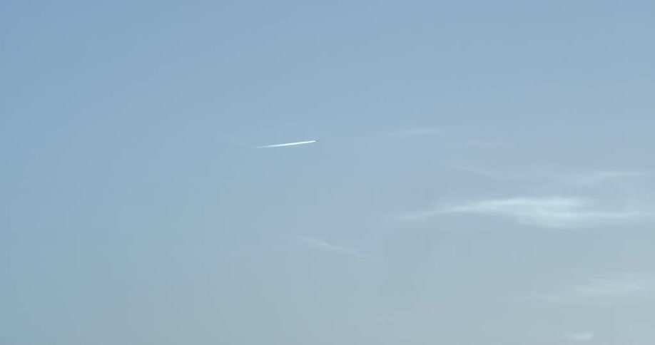 A plane is leaving a vapor trail as it flies in the sky on a sunny day