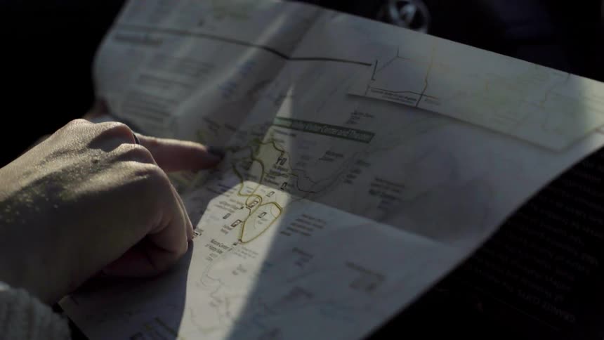A woman follows a map line with her finger
