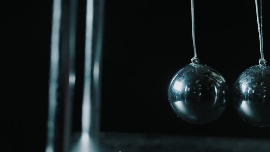 A metal ball is bouncing against others as it hangs in a newton's cradle