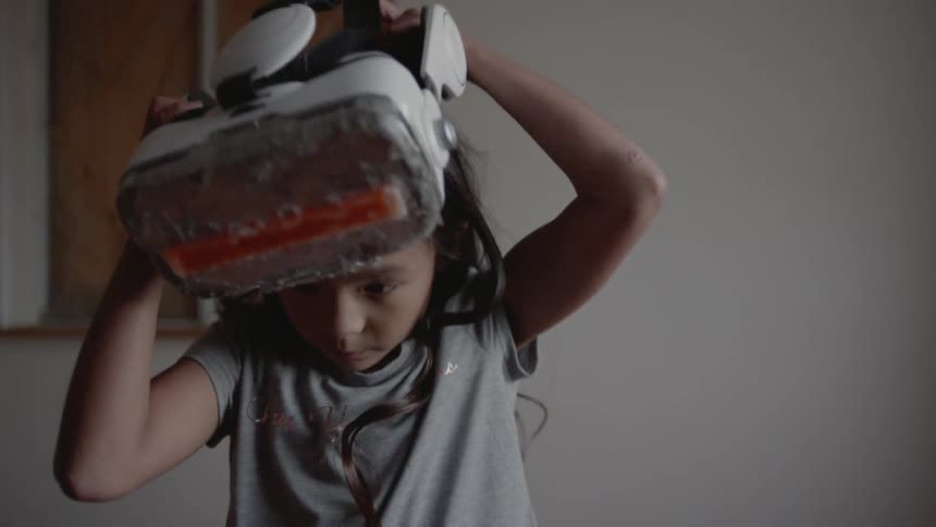 Wind blows a girls hair as she puts on vr glasses