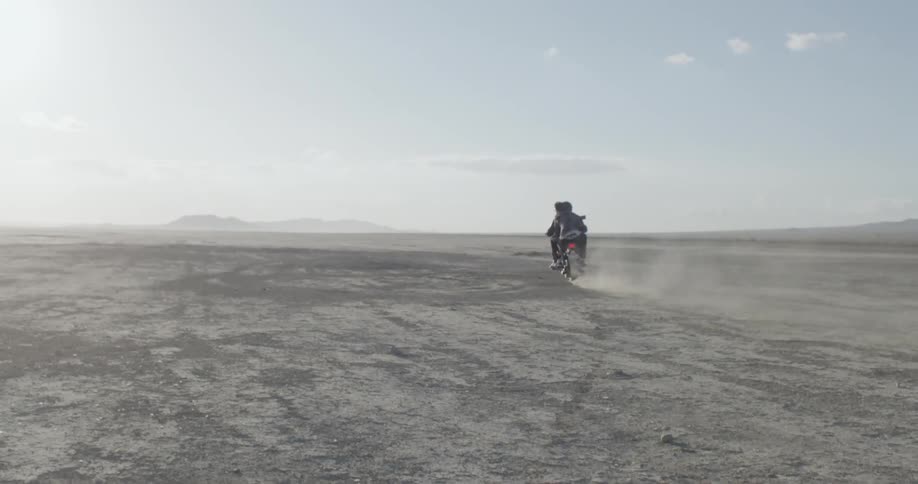 A motorcyclist rides across a desert field