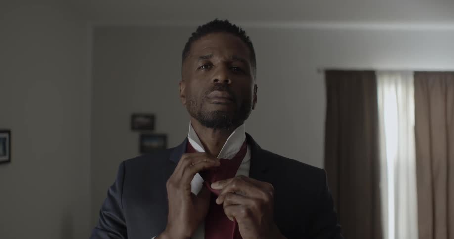A man in a suit puts on a tie