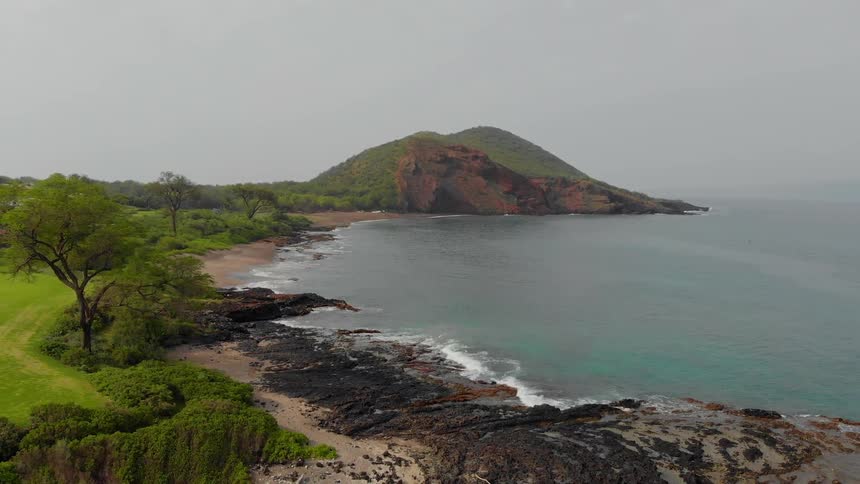 Waves are lapping the beach of an island on a hazy day