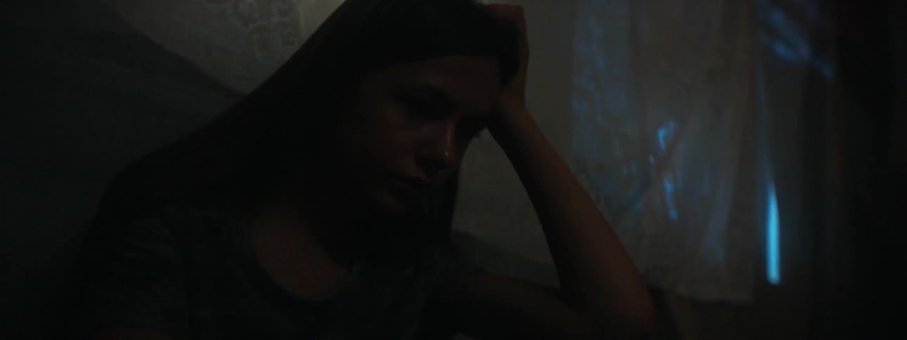 A woman leans against the window in the dark