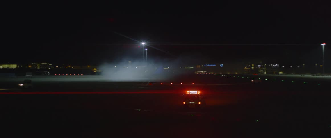 Cop car with lights on drives in a large parking lot