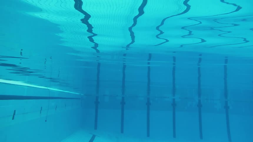 A swimming pool's lane lines reflect on the surface