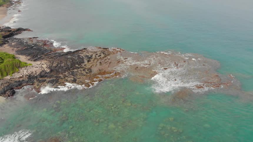 The waves crash against the rocks near the shore