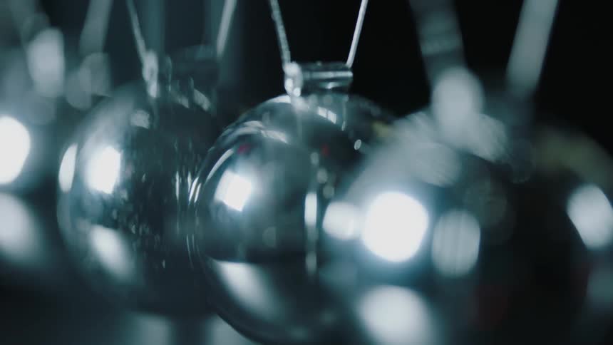 Light reflects on the metal balls in a newton's cradle