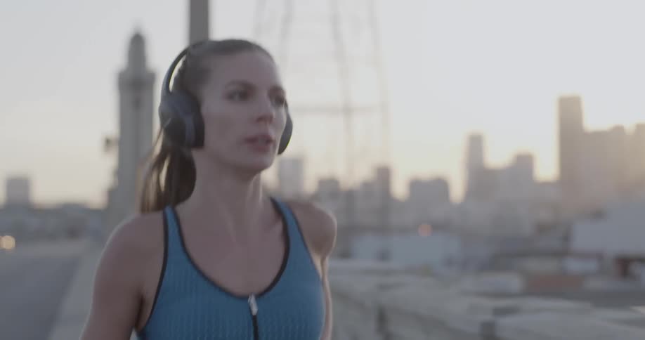 A woman jogs in a city at sunset