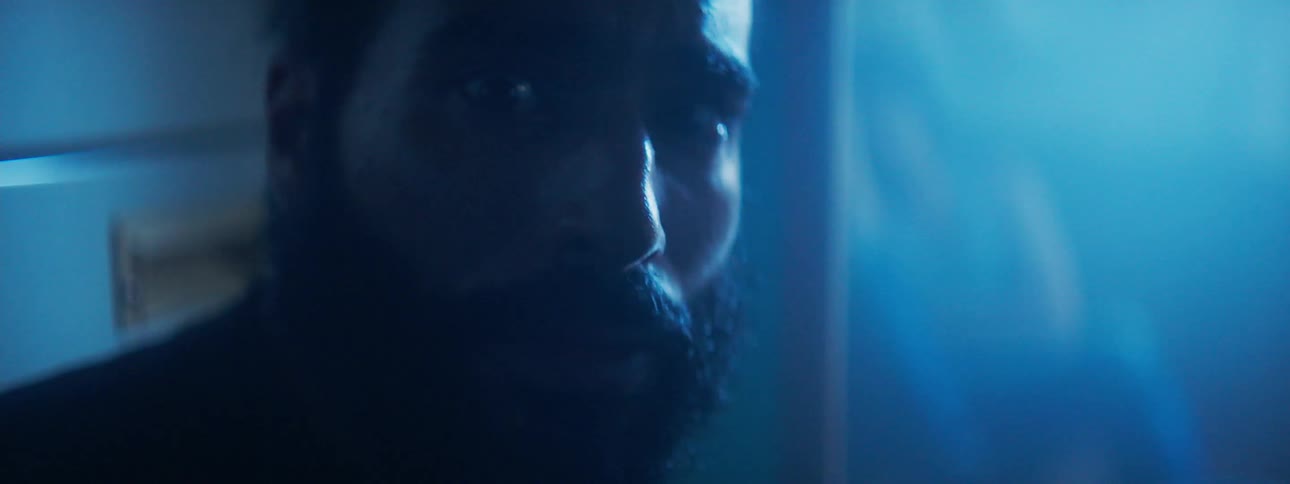 A light shines on a bearded man's face then fades