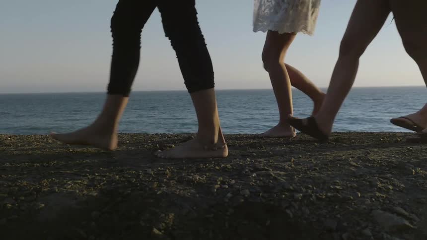 People walk on a beach at sunset