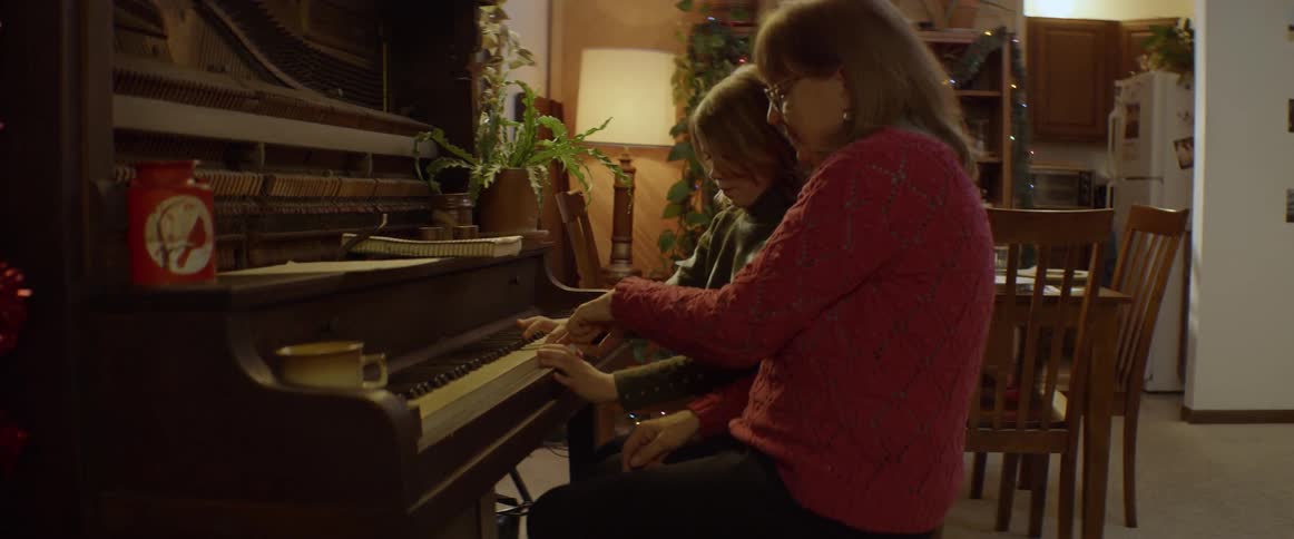 A woman and boy play a piano