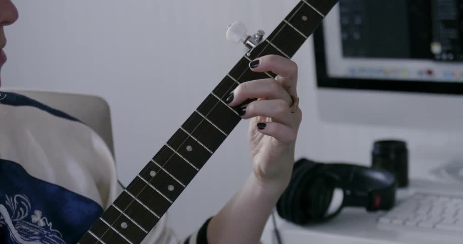 Woman moving her fingers on guitar strings